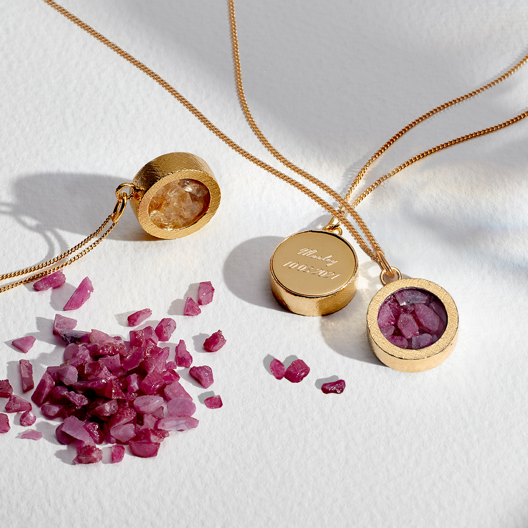 Ruby birthstones next to gold amulet necklace